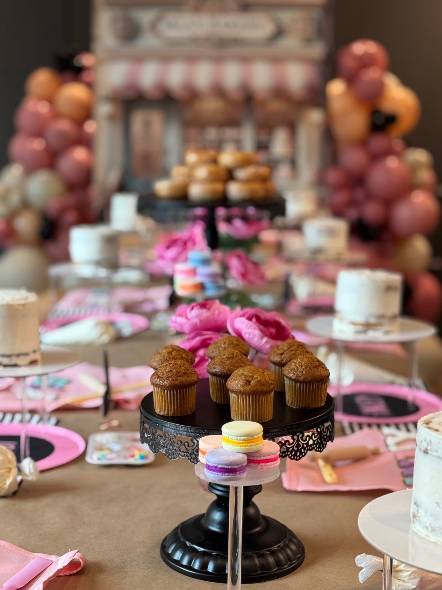 Cake stand with muffins and macarons among pink flowers